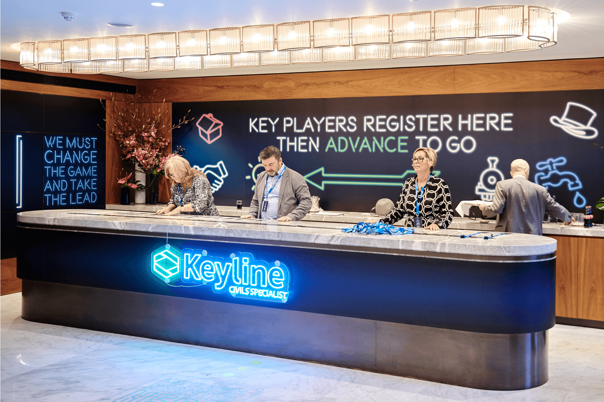 4 individuals stood at the registration desk, ready to help players find their name tags and lanyards