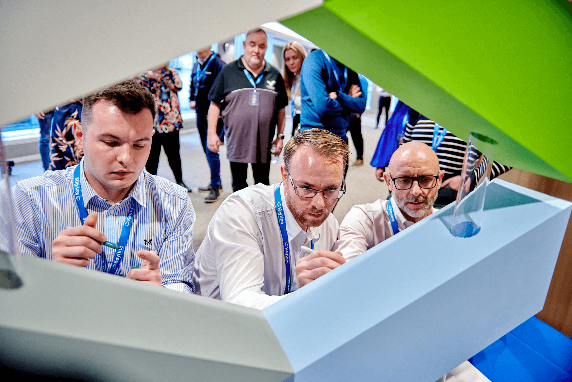 Three men getting involved in an activity at Keyline's corporate event whilst being watched by a group of individuals.